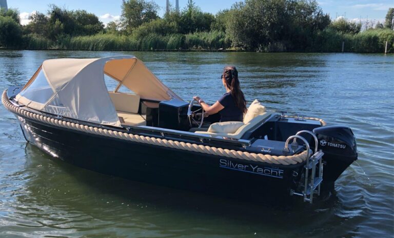 Donkere Silver 495 met cabrioletkap en buitenboordmotor op het water.